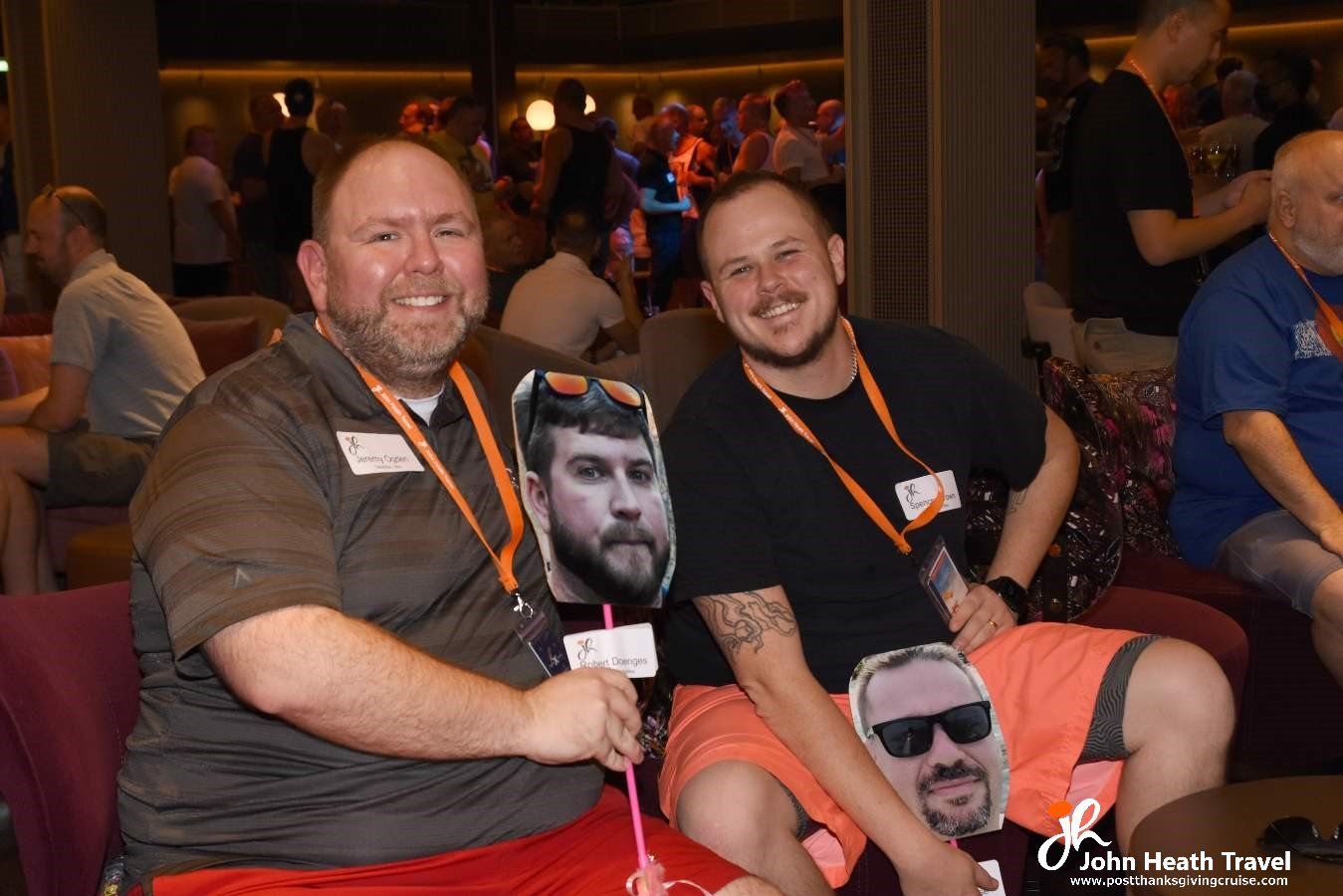 Two men are sitting next to each other on a couch holding a picture of their faces.