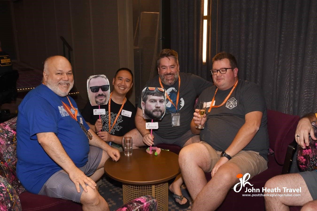 A group of men are sitting around a table with their faces on sticks.