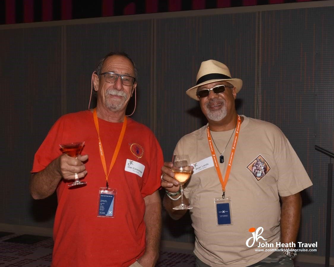 Two men are standing next to each other holding wine glasses.