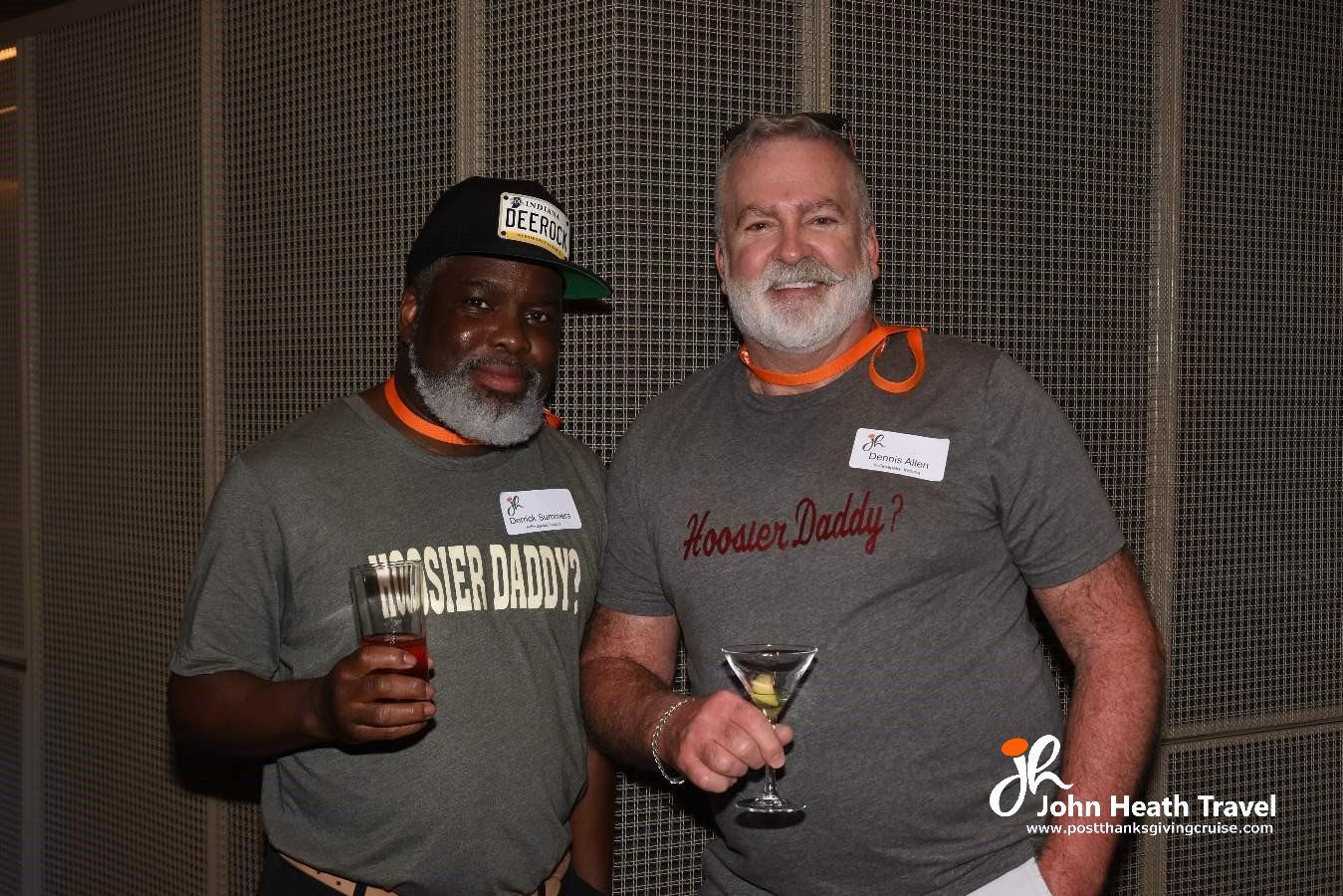 Two men are standing next to each other and one of them is holding a martini glass.