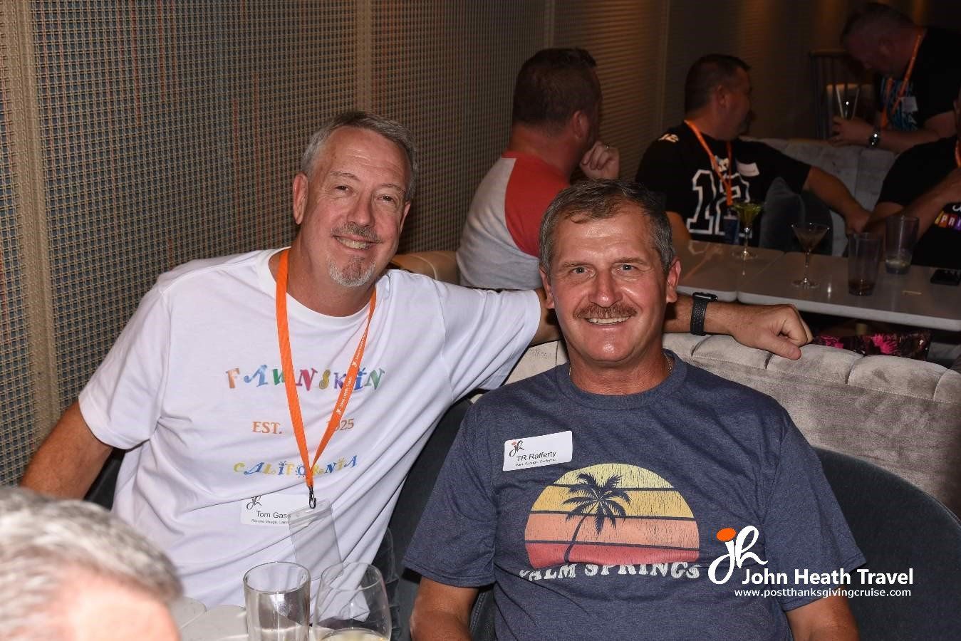 Two men are posing for a picture and one has a name tag that says john heath travel