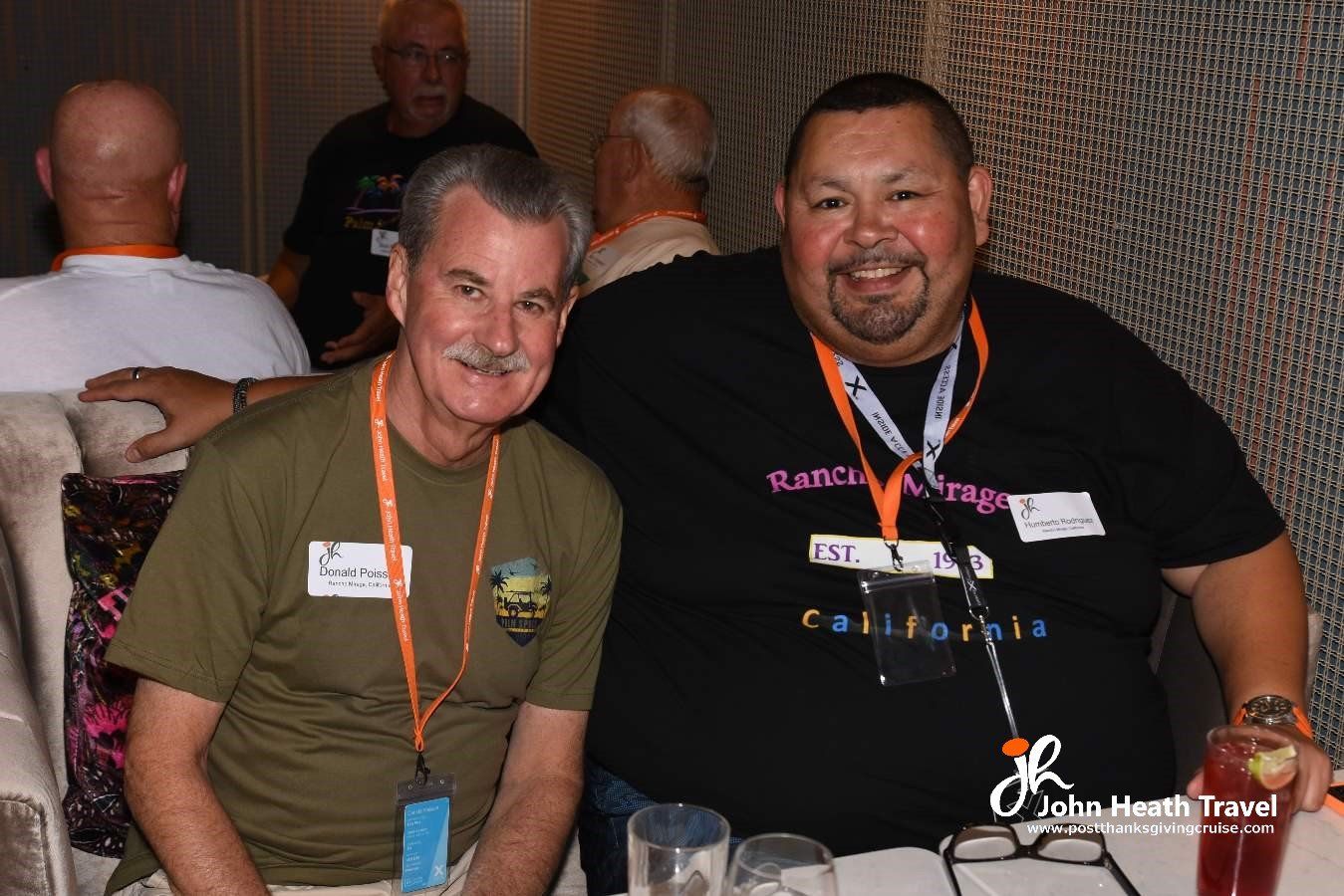 Two men are posing for a picture while sitting at a table.