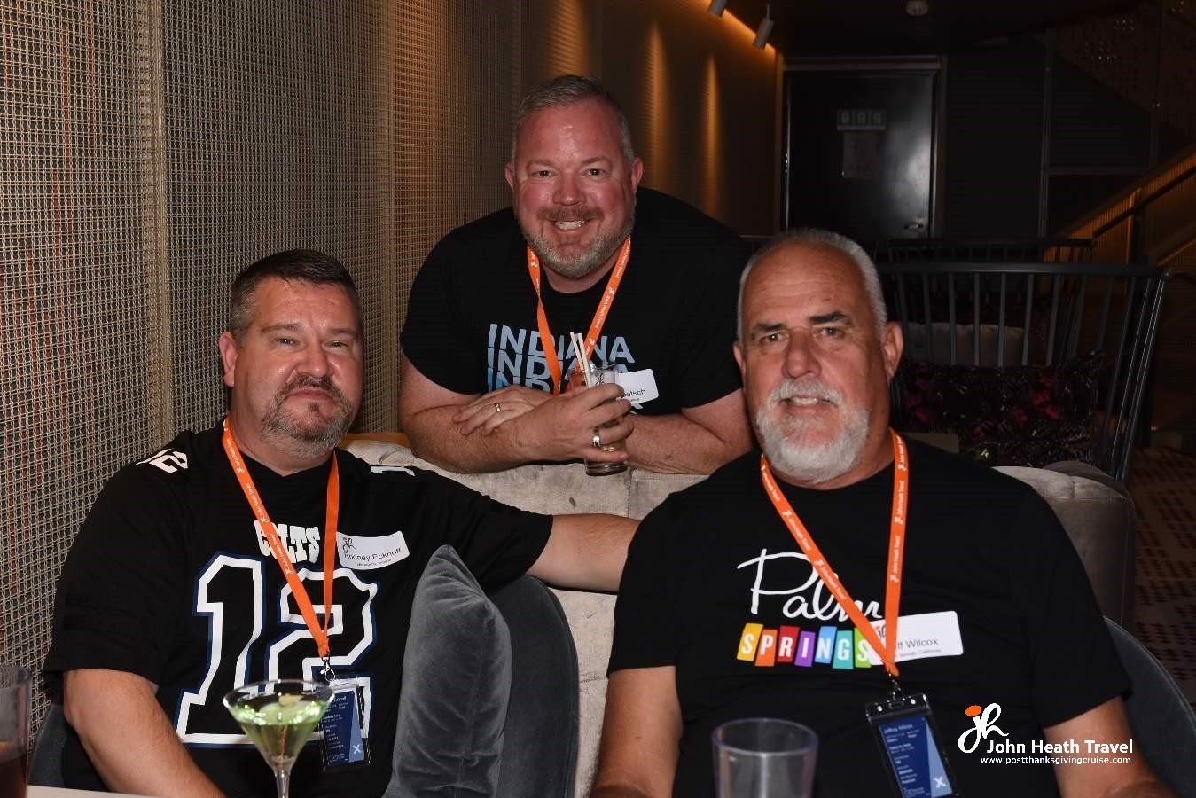 Three men wearing black shirts with the number 12 on them are posing for a picture.