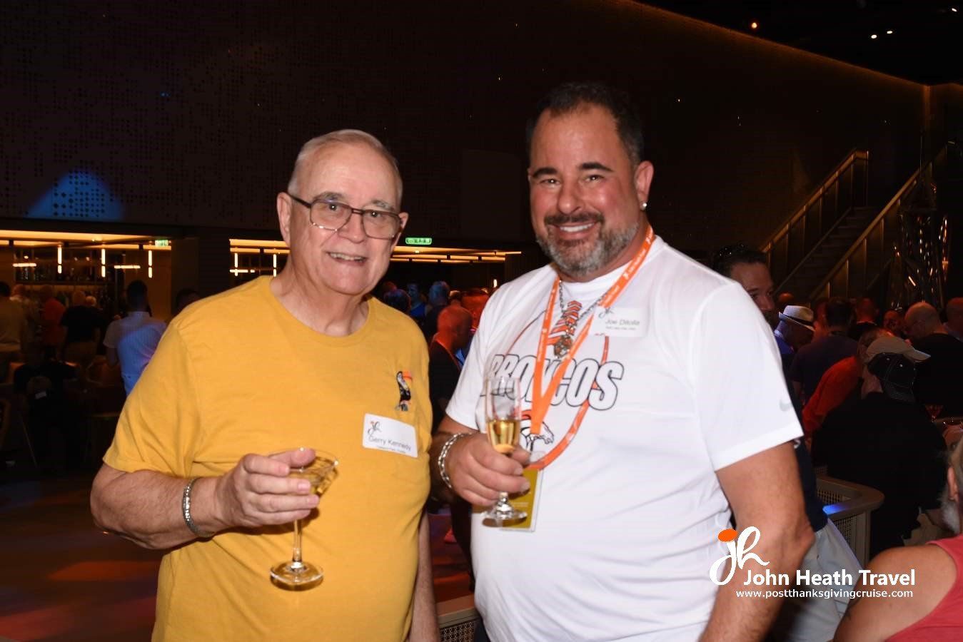 Two men are standing next to each other holding wine glasses.
