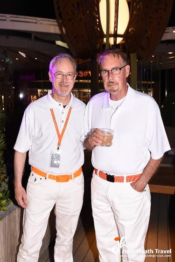 Two men wearing white shirts and orange belts are standing next to each other.