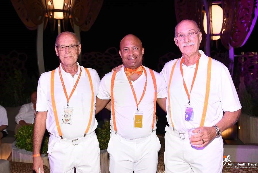 Three men wearing white shirts and suspenders pose for a picture