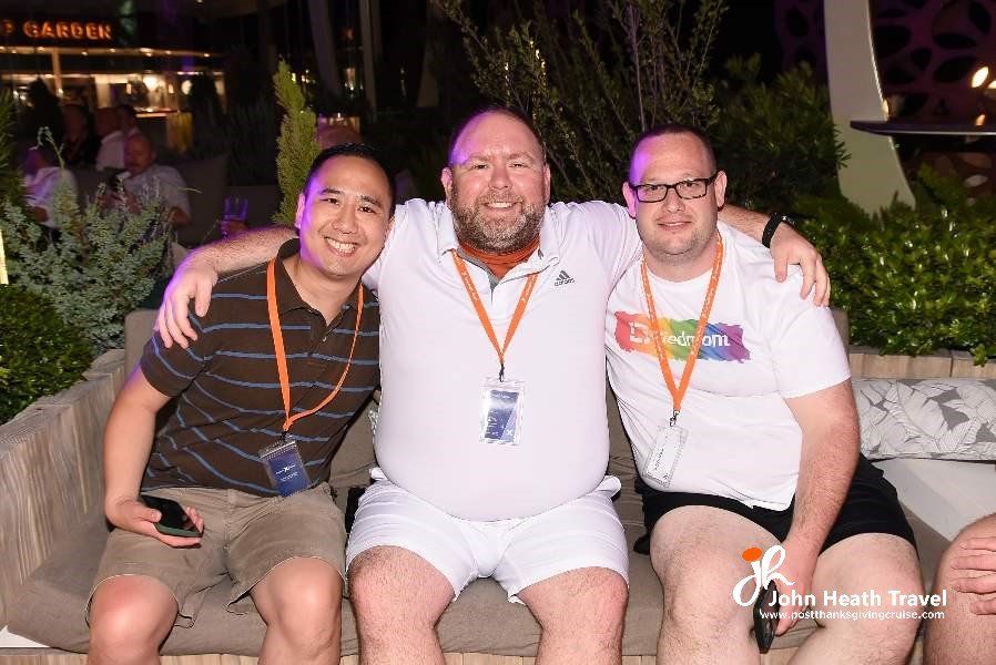 Three men are posing for a picture while sitting on a couch.