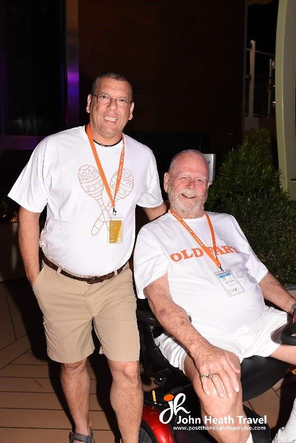 Two men are posing for a picture while one of them is in a wheelchair.