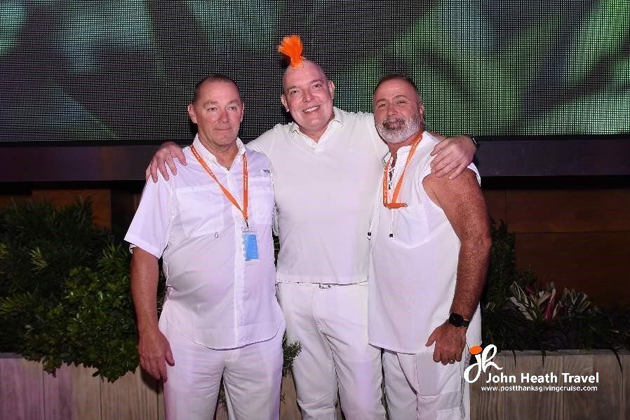 Three men wearing white shirts and pants are posing for a picture.