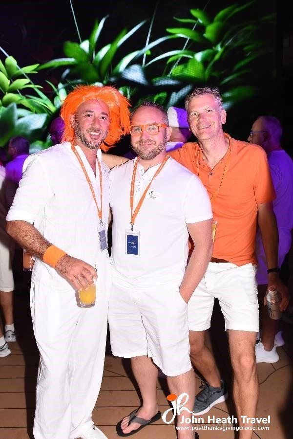 Three men are posing for a picture at a party . one of the men is wearing an orange wig.
