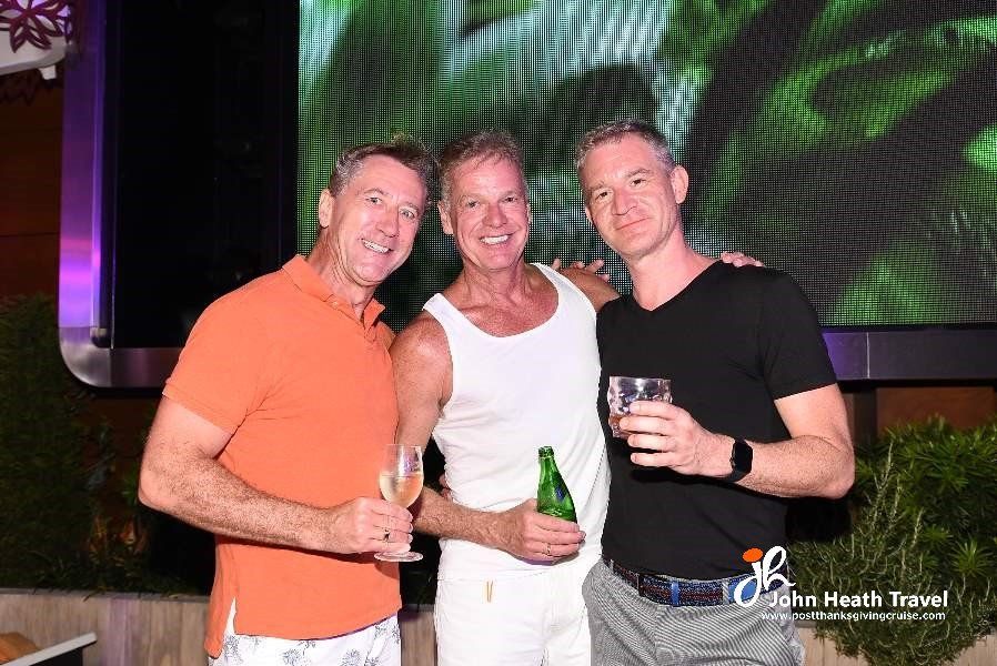 Three men are posing for a picture while holding beer bottles.