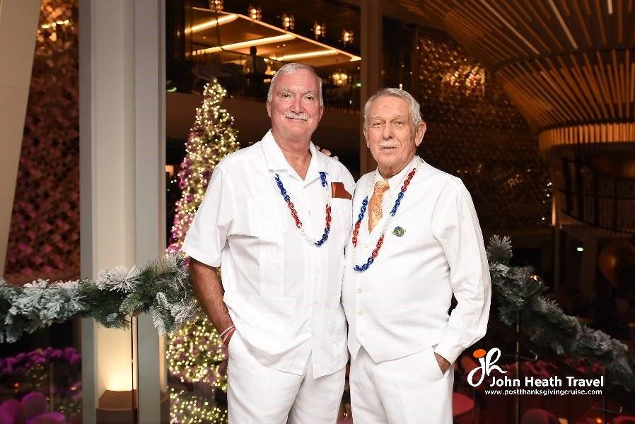 Two men are posing for a picture in front of a christmas tree.