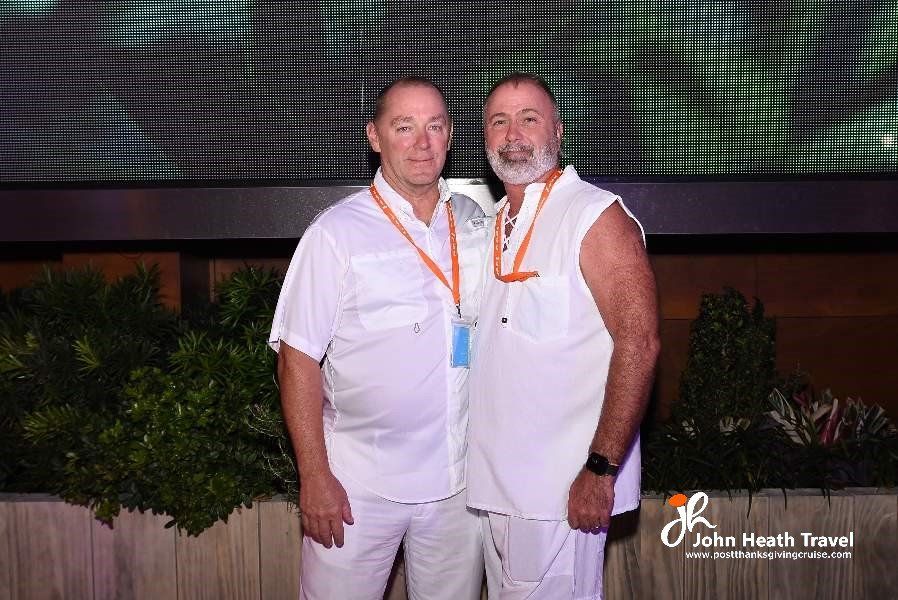 Two men are standing next to each other in white shirts.