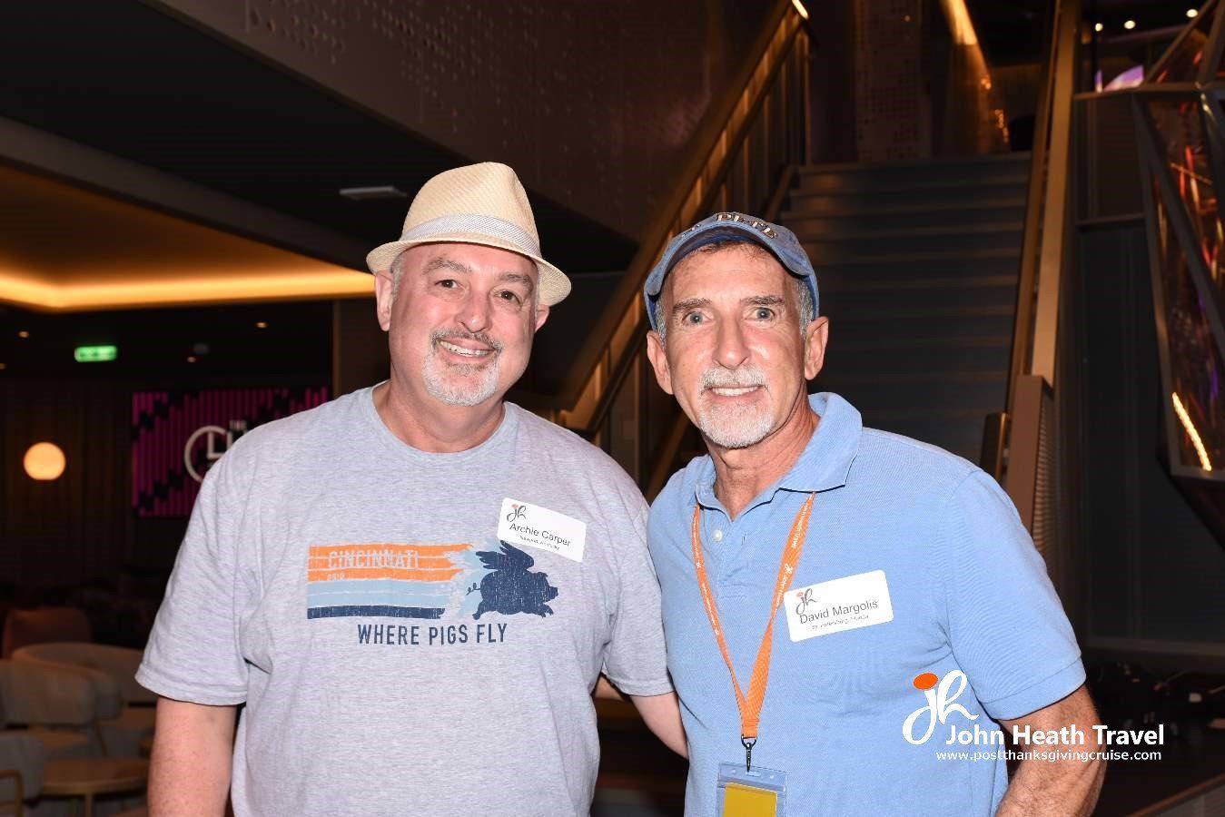 Two men are posing for a picture in front of a staircase.