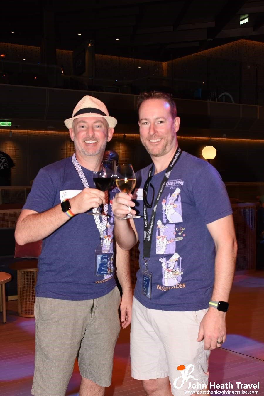 Two men are standing next to each other holding wine glasses.