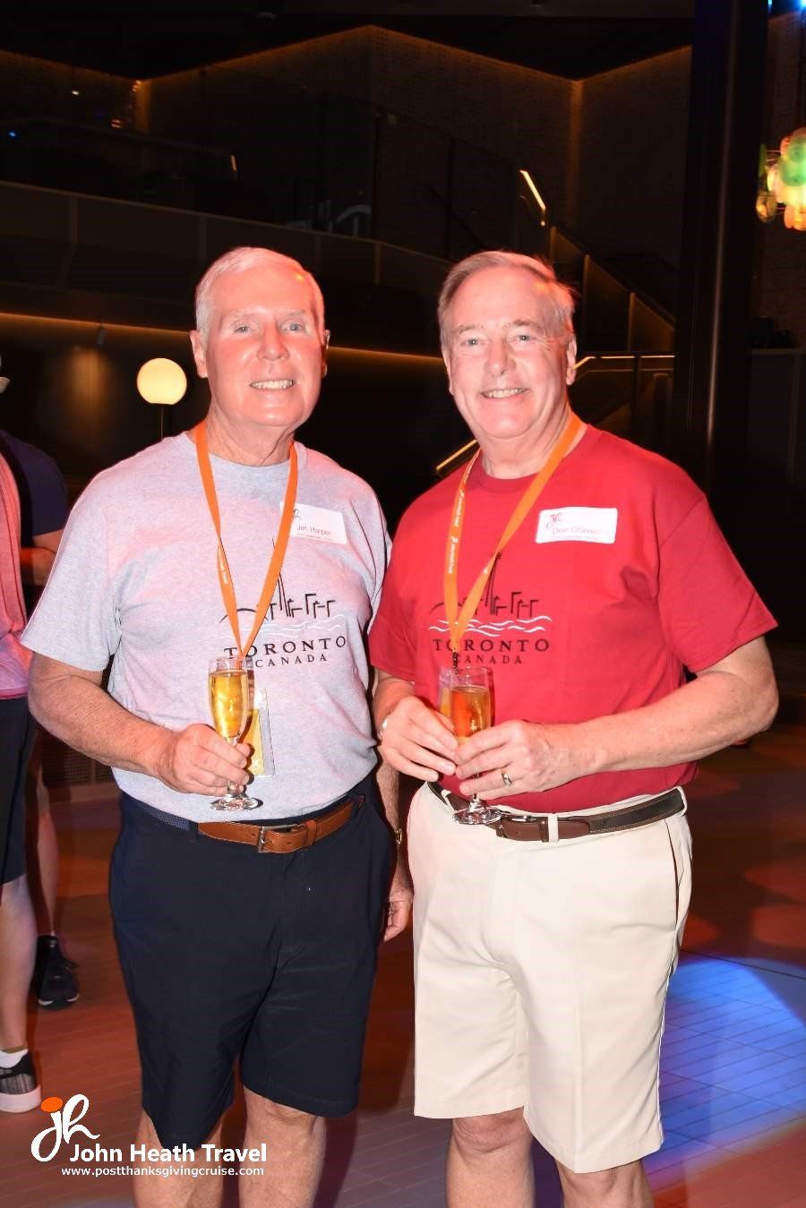 Two men are standing next to each other holding champagne glasses.