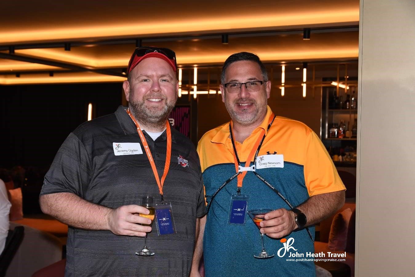 Two men are standing next to each other holding wine glasses.