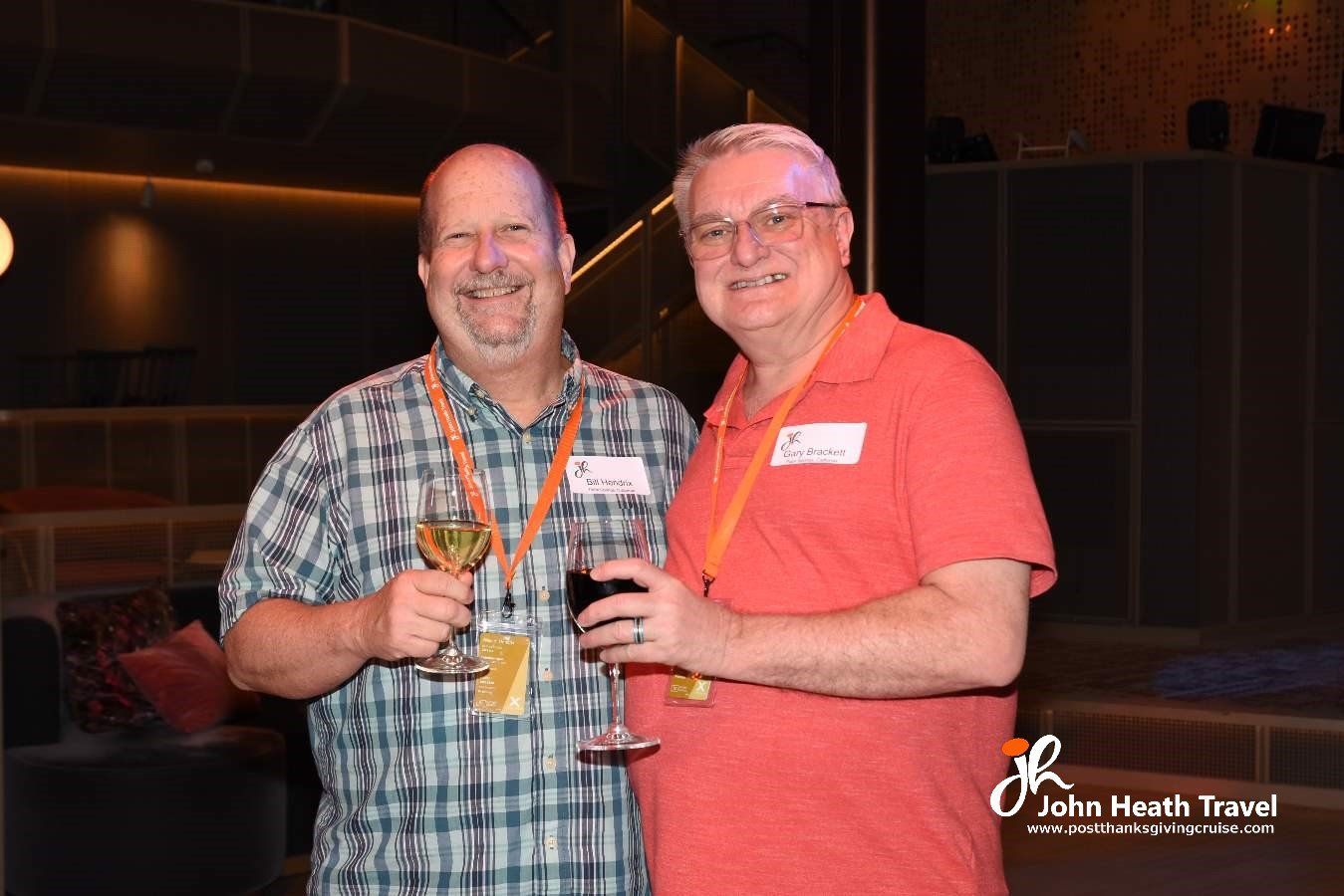 Two men are standing next to each other holding wine glasses.