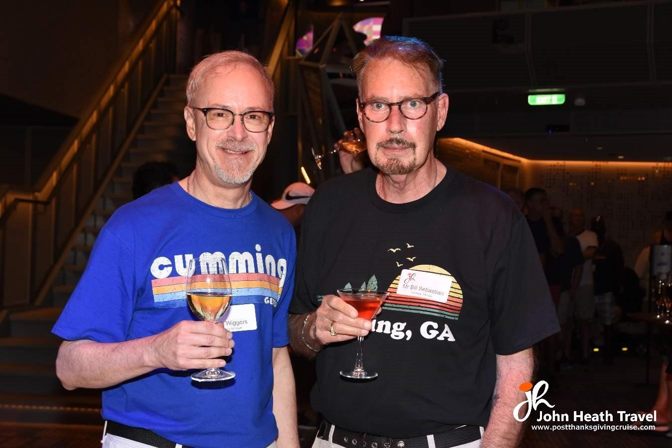 Two men are standing next to each other holding wine glasses.