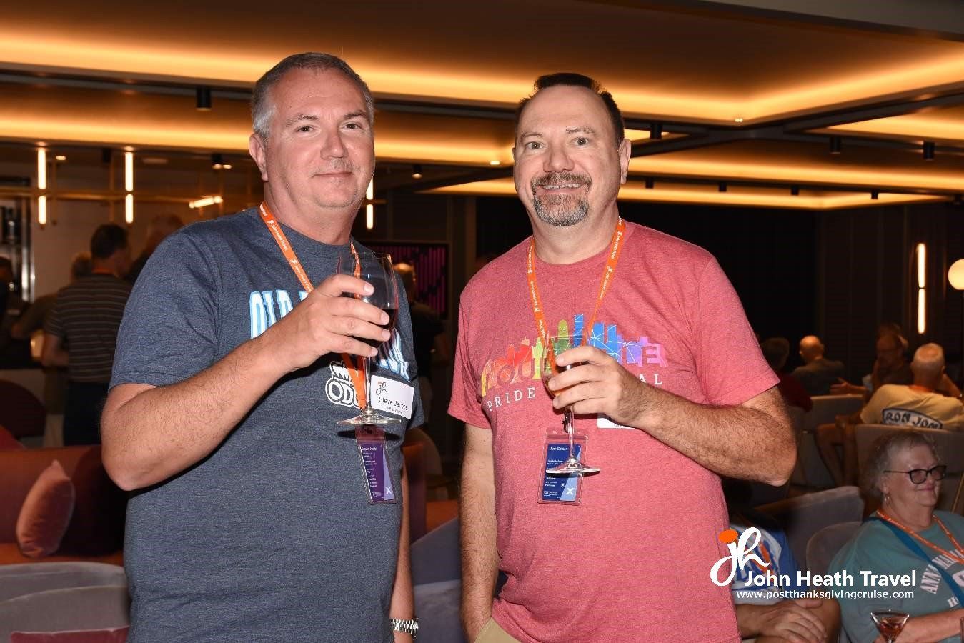 Two men are standing next to each other holding wine glasses.