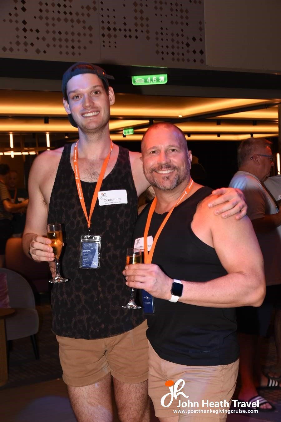 Two men are posing for a picture while holding champagne glasses.