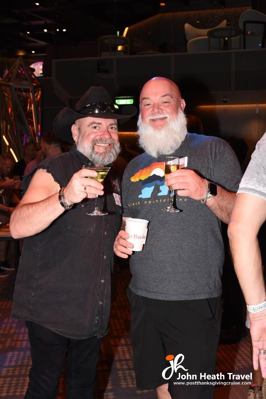 Two men with beards are standing next to each other holding drinks.