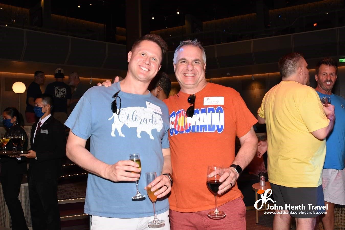 Two men are posing for a picture while holding wine glasses.