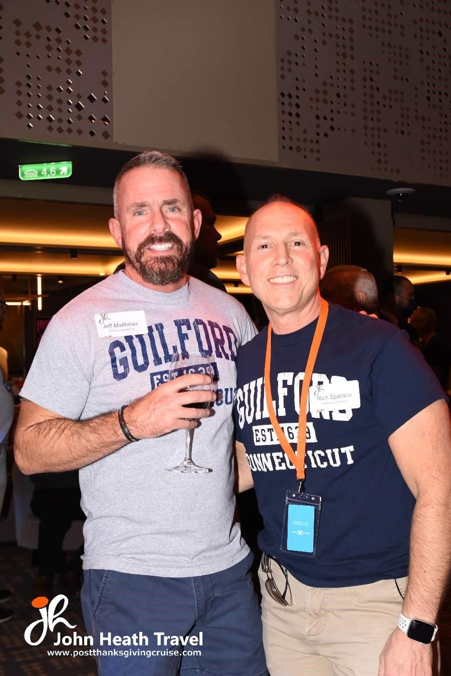 Two men are posing for a picture together and one of them is wearing a gulfford shirt.
