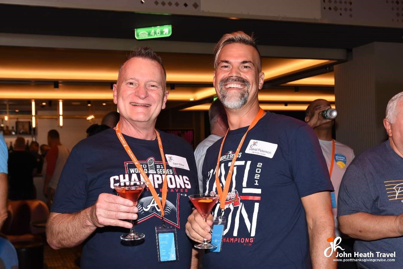 Two men are standing next to each other holding wine glasses.