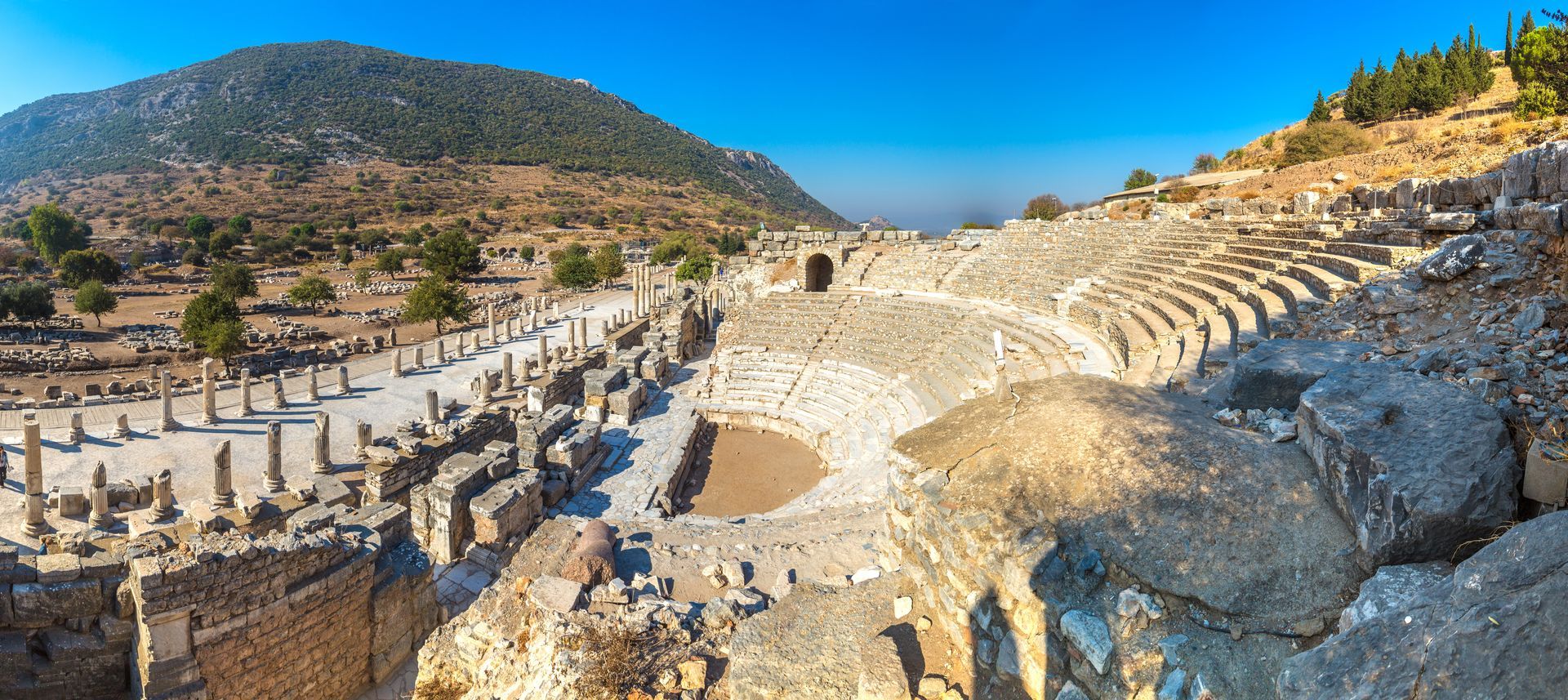 An aerial view of an ancient amphitheater in the middle of a mountain.