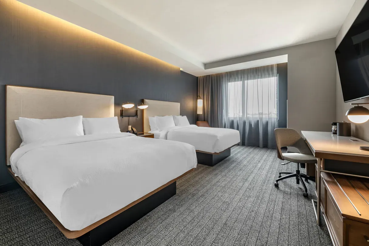 A hotel room with two beds , a desk and a television.
