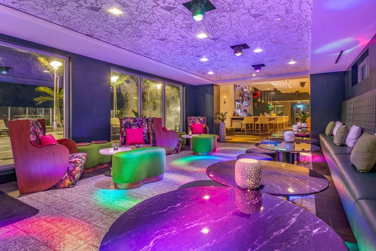 A living room filled with furniture and tables with purple and green lights.