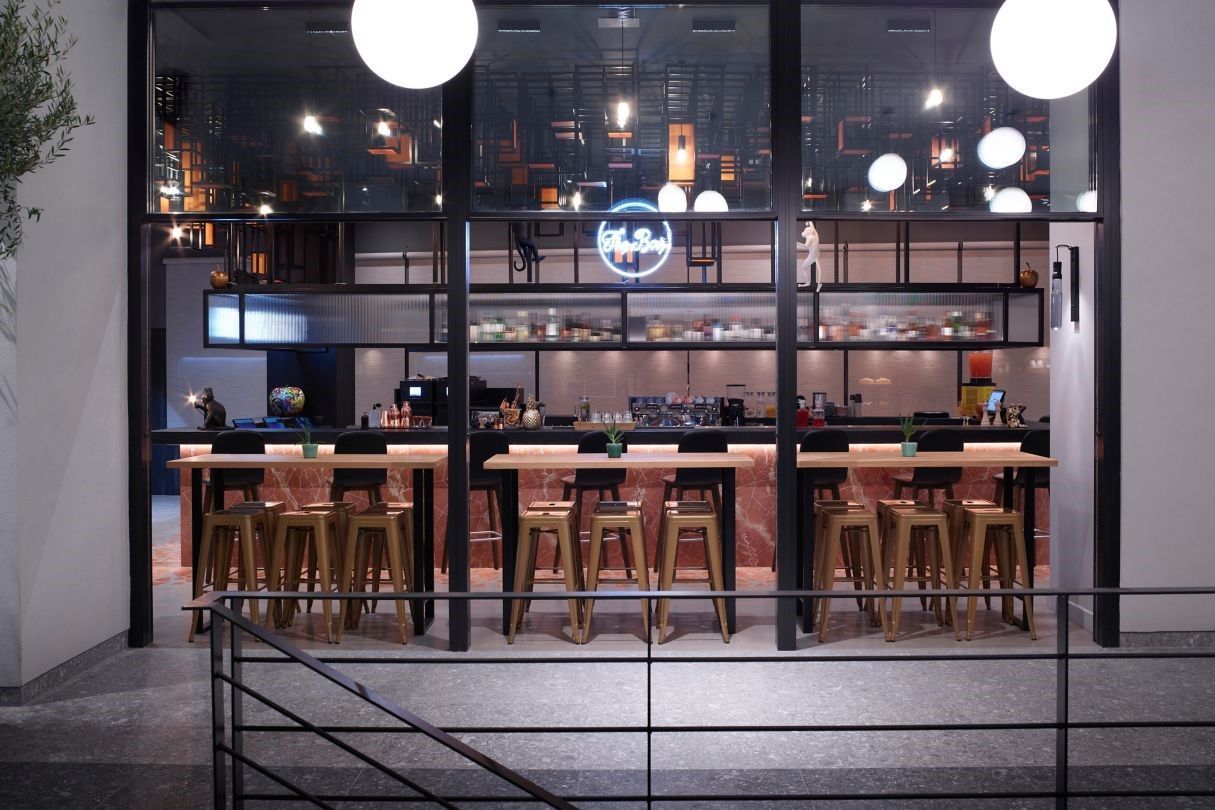 A restaurant with tables and stools in front of a large window