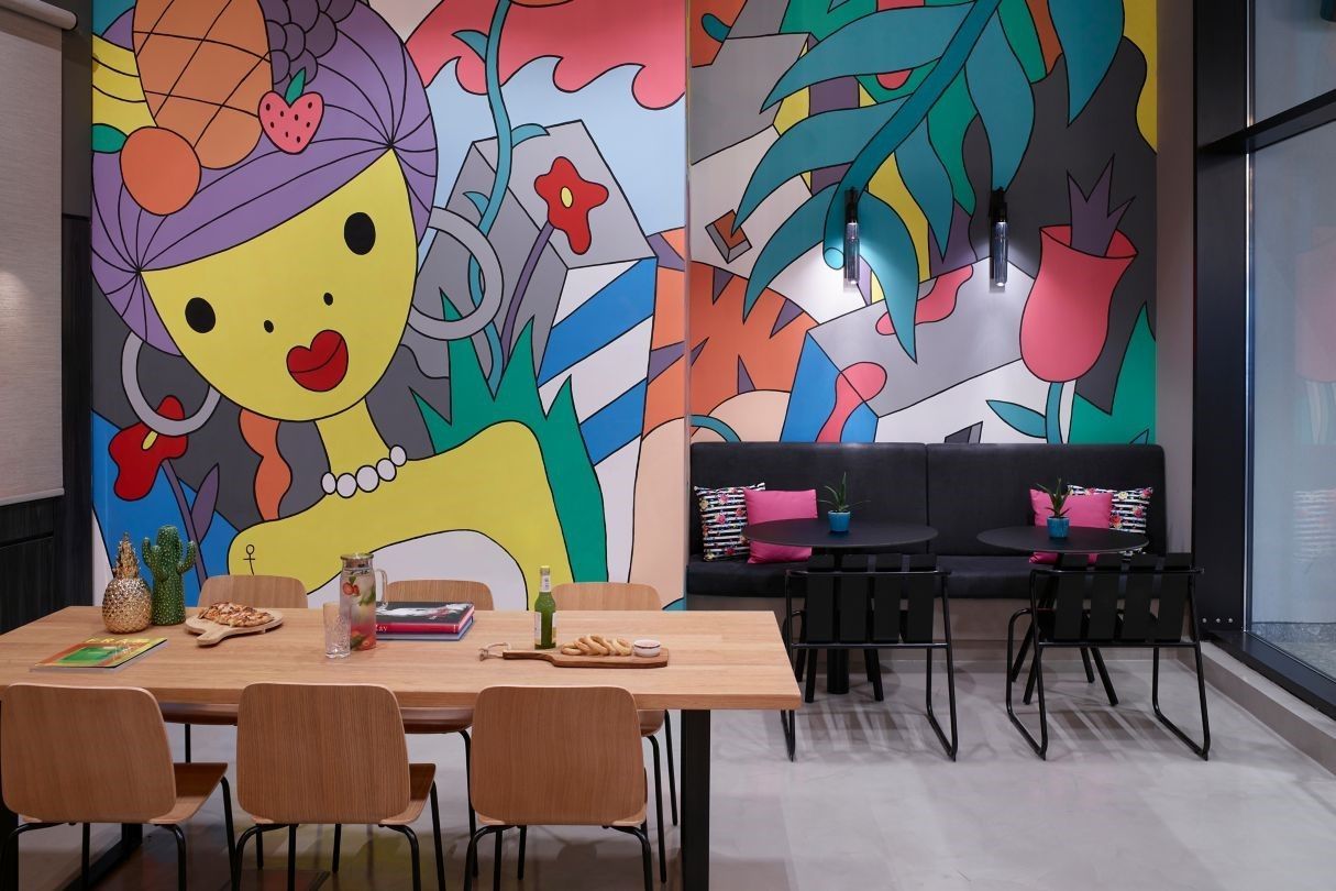 A room with a table and chairs and a mural on the wall