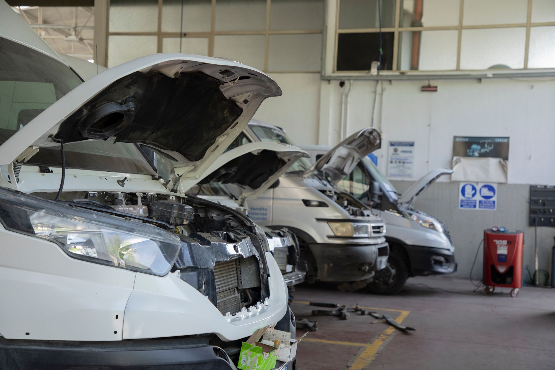 Tre furgoni bianchi con il cofano aperto all'interno di un garage.