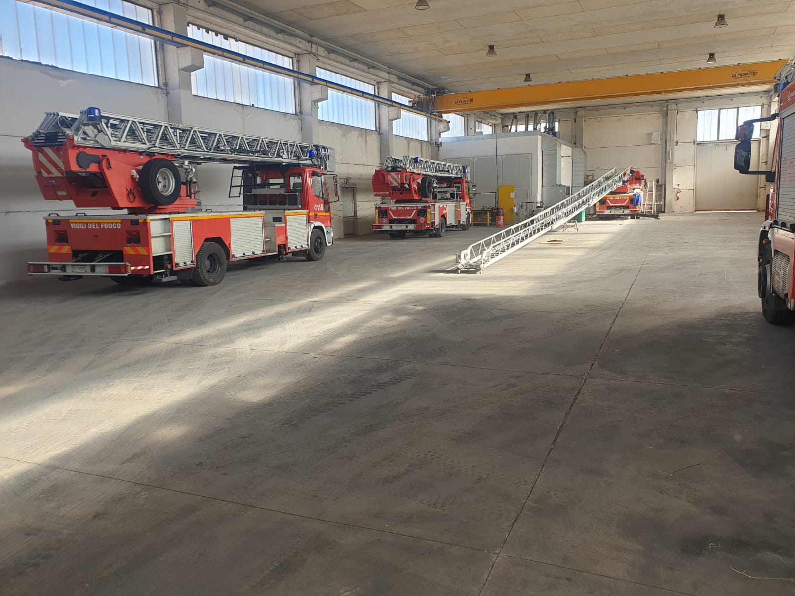 Interno della caserma dei pompieri con numerosi camion dei pompieri rossi e bianchi.