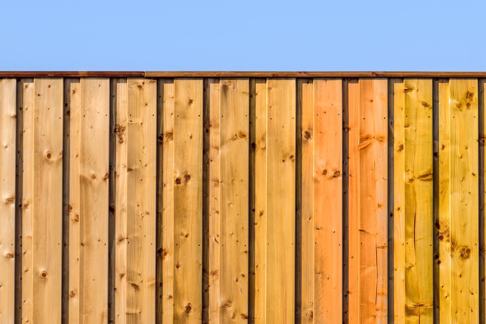 An image of a shadowbox wood fence with blue sky in background