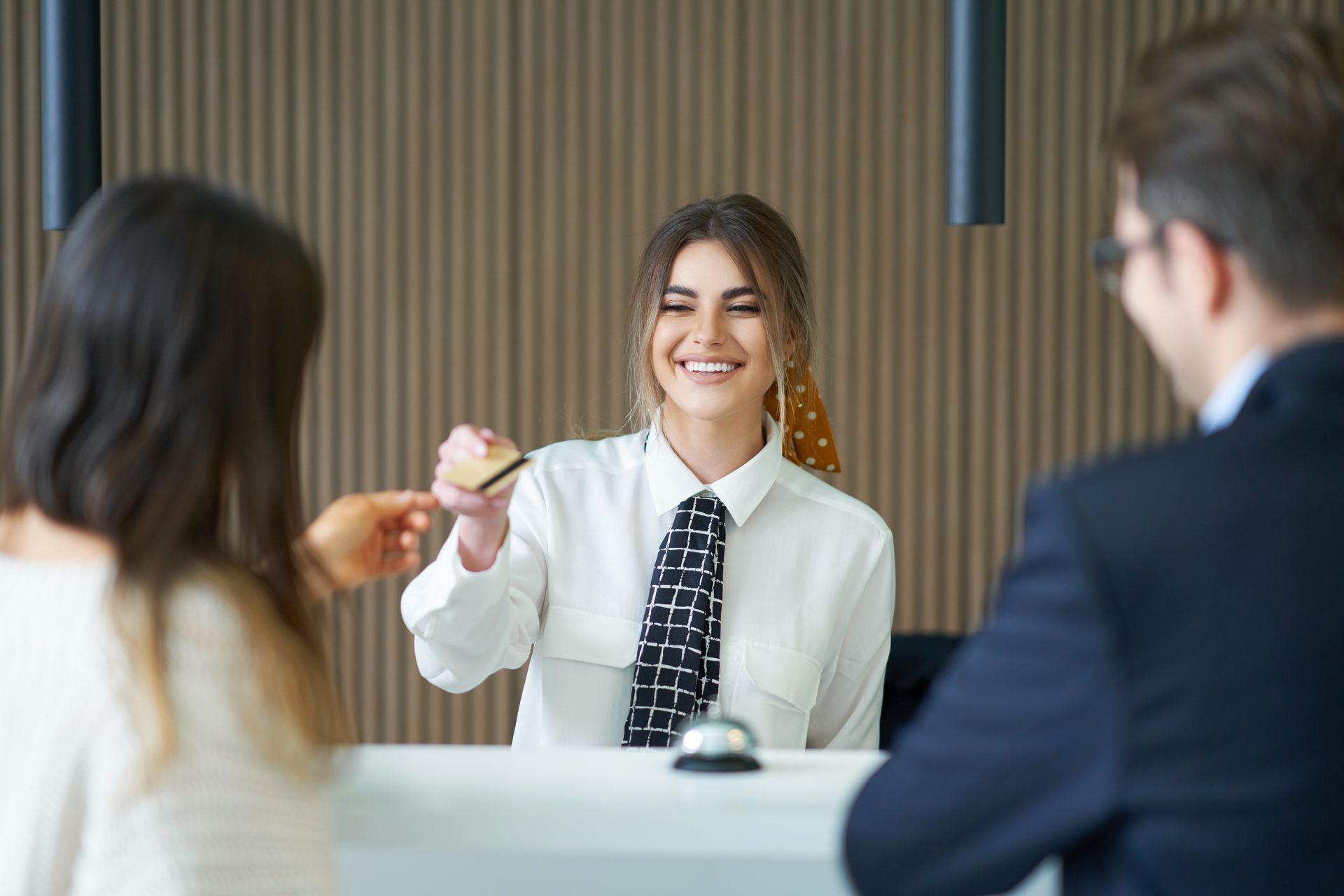 The front desk staff gives the guests their guest room key card.