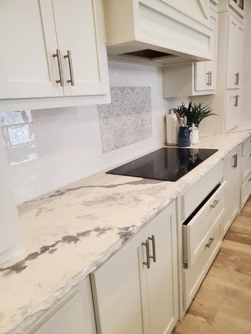 A kitchen with white cabinets and a stove top oven.