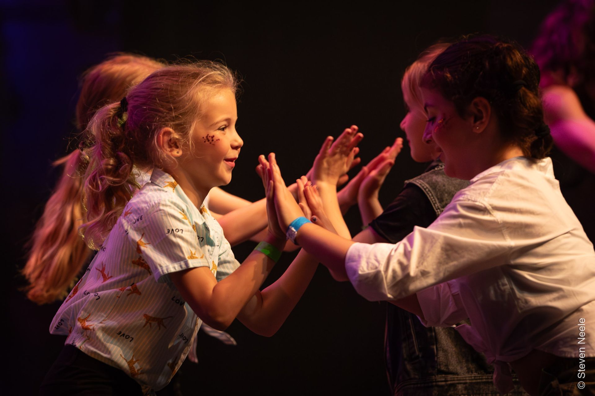 Een groep kinderen geeft elkaar een high five op een podium.