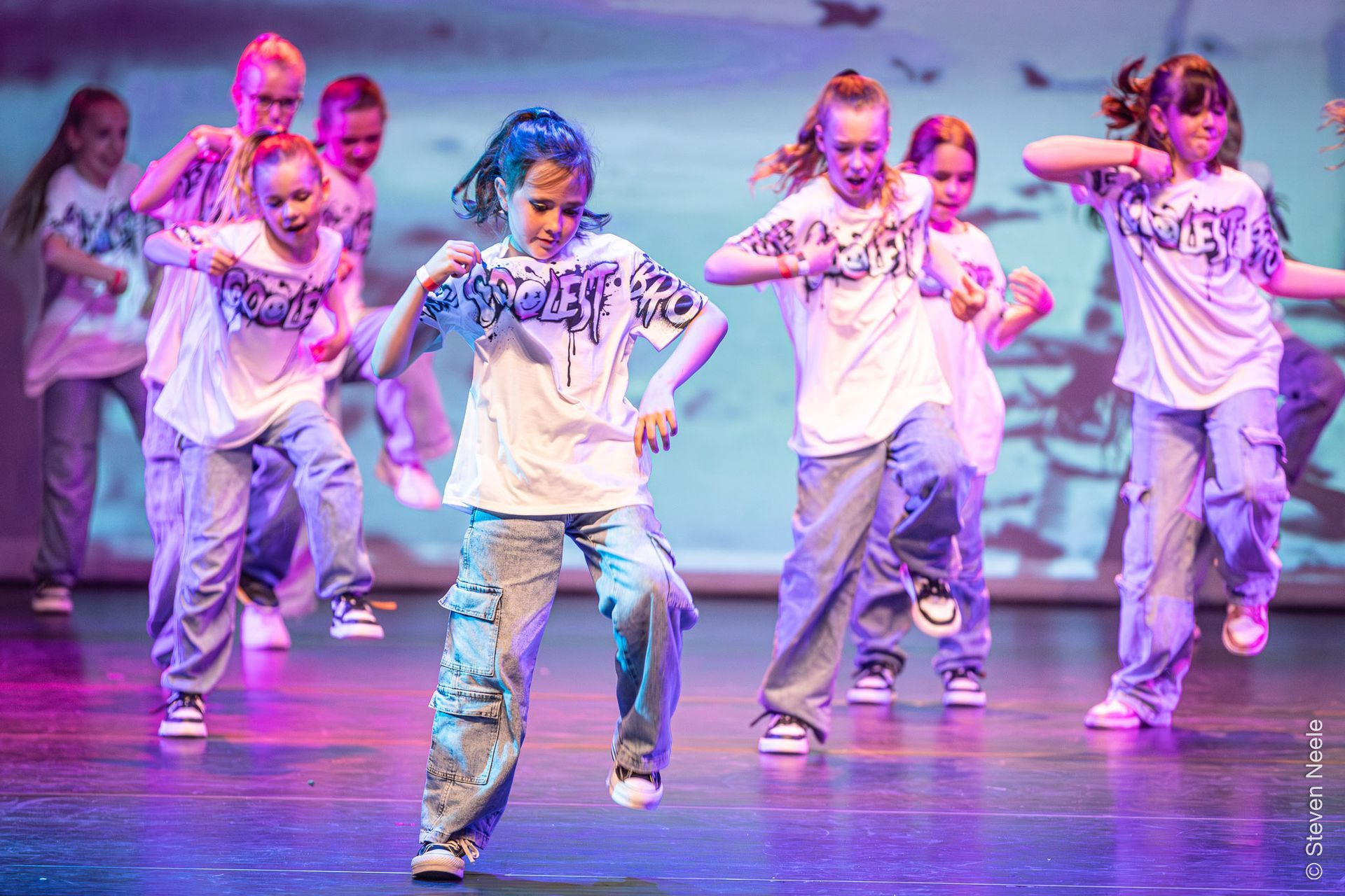 Een groep jonge meisjes danst op een podium.