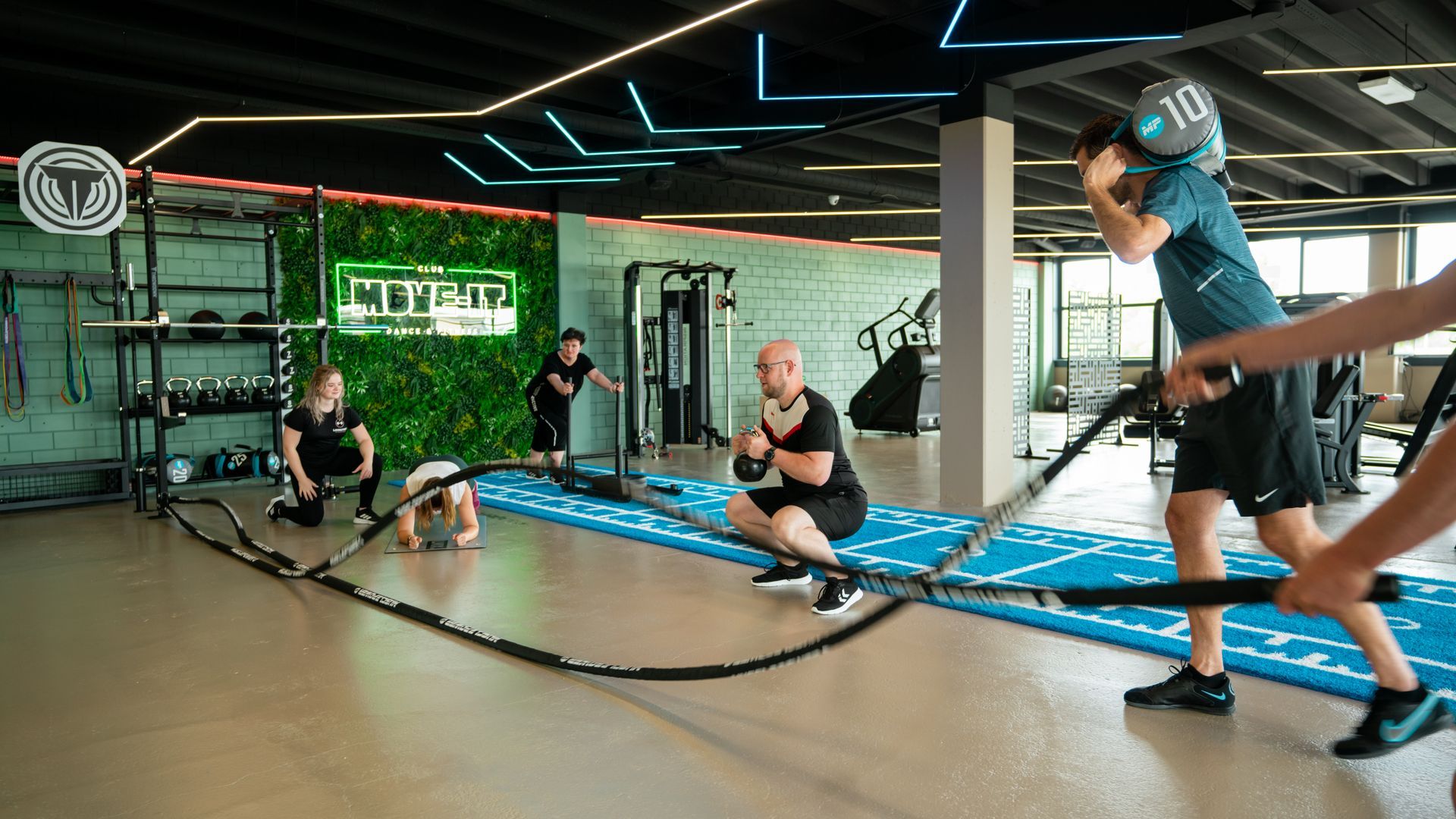 Twee vrouwen zitten op yogamatten op de vloer van een kamer.
