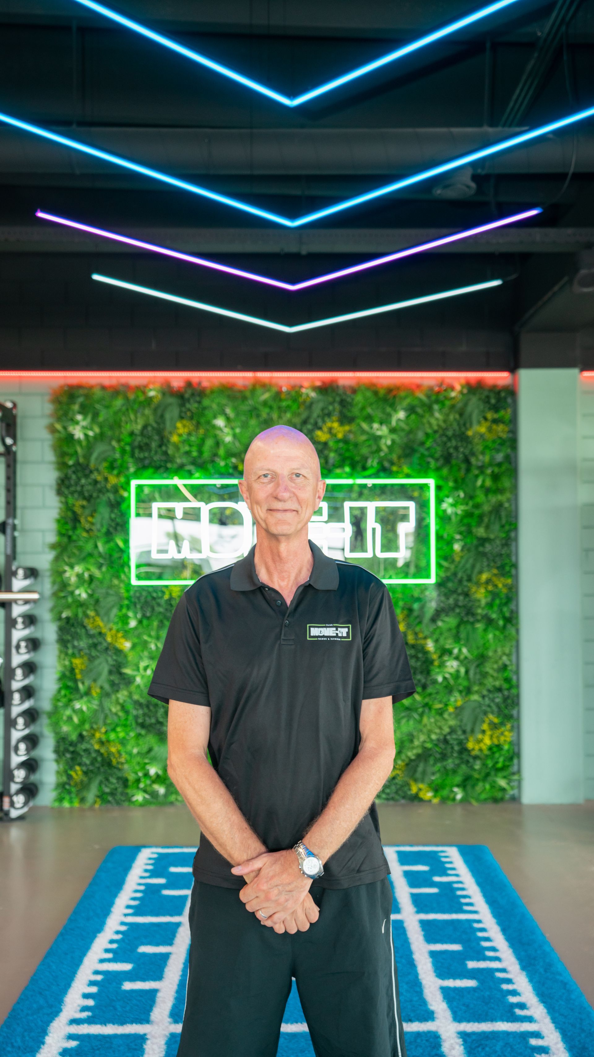 Een vrouw, gekleed in een zwart t-shirt met het woord flyline erop, staat voor een raam.