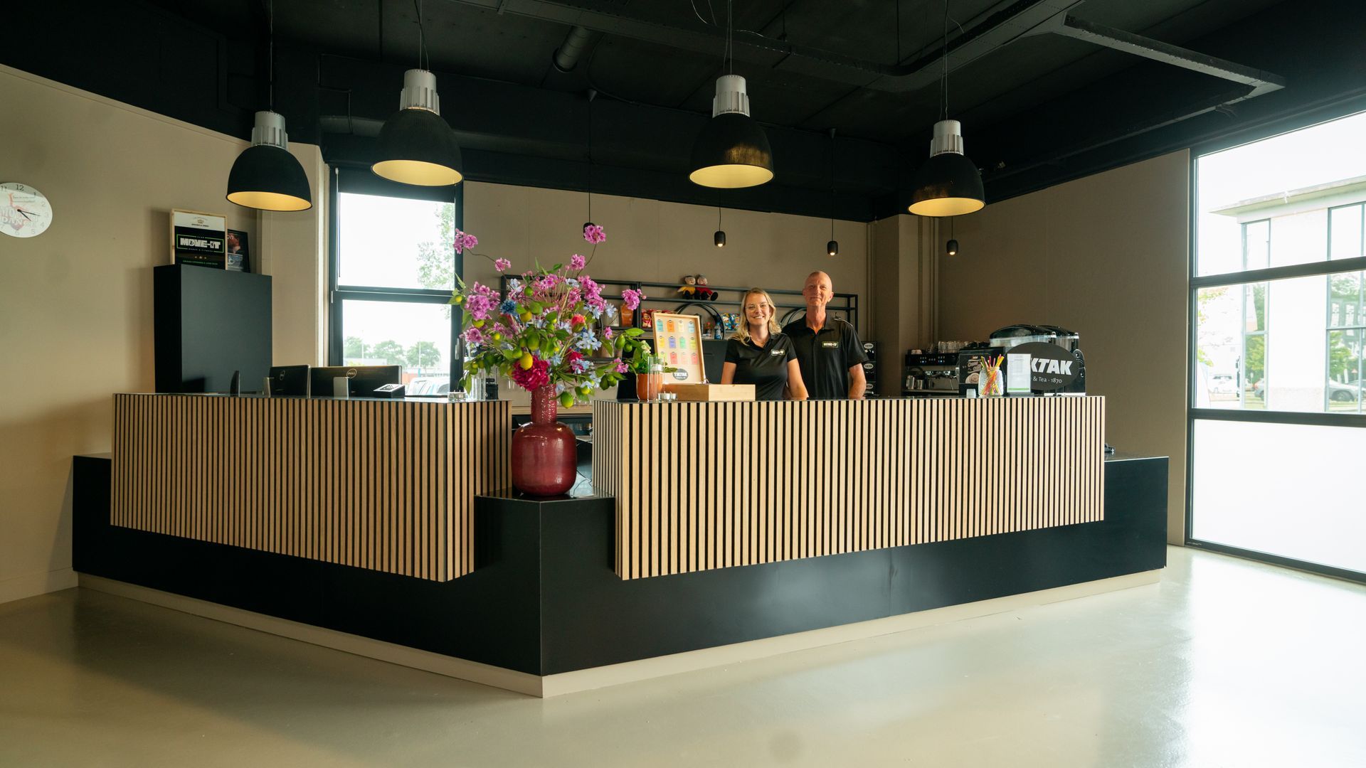 Een groep mensen doet squats op rode matten in een sportschool.