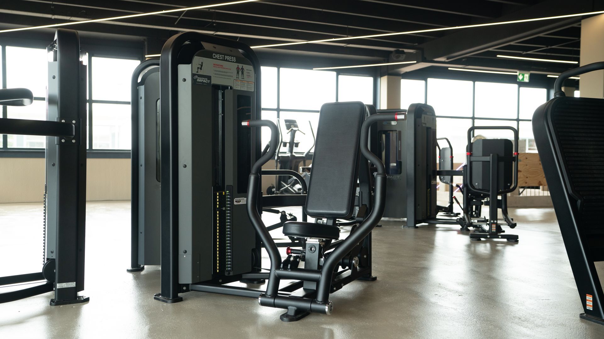 Een sportschool met veel fitnessapparatuur en een bank