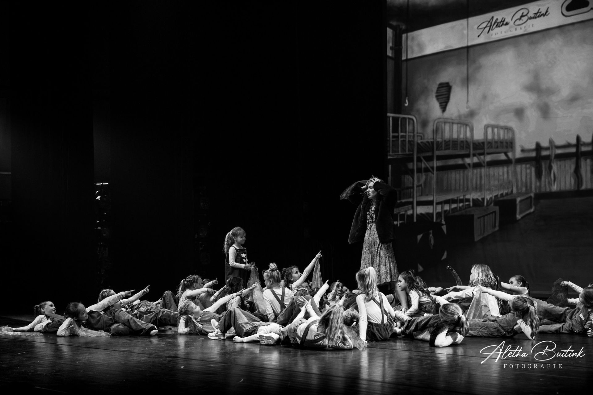 Op een zwart-witfoto is een groep kinderen te zien die op een podium danst.