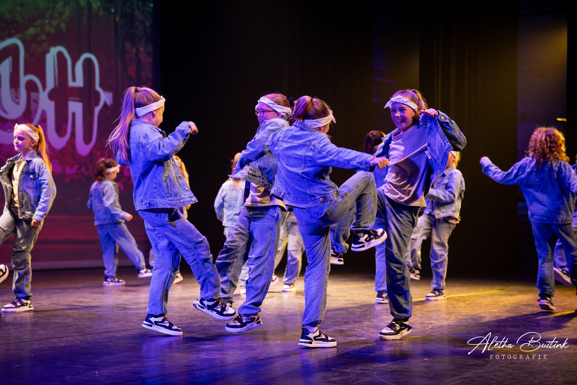 Een groep jongeren danst op een podium.