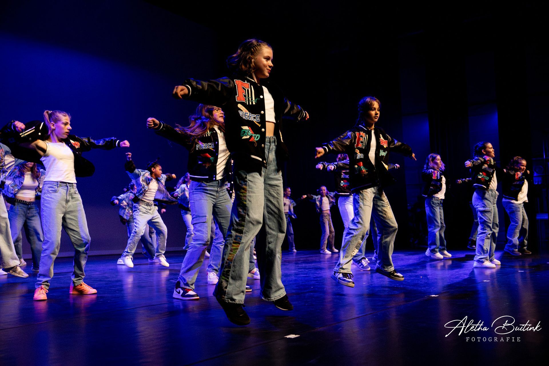 Een groep jongeren danst op een podium.