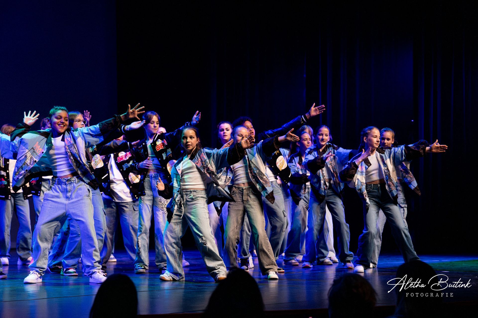 Een groep jongeren danst op een podium.