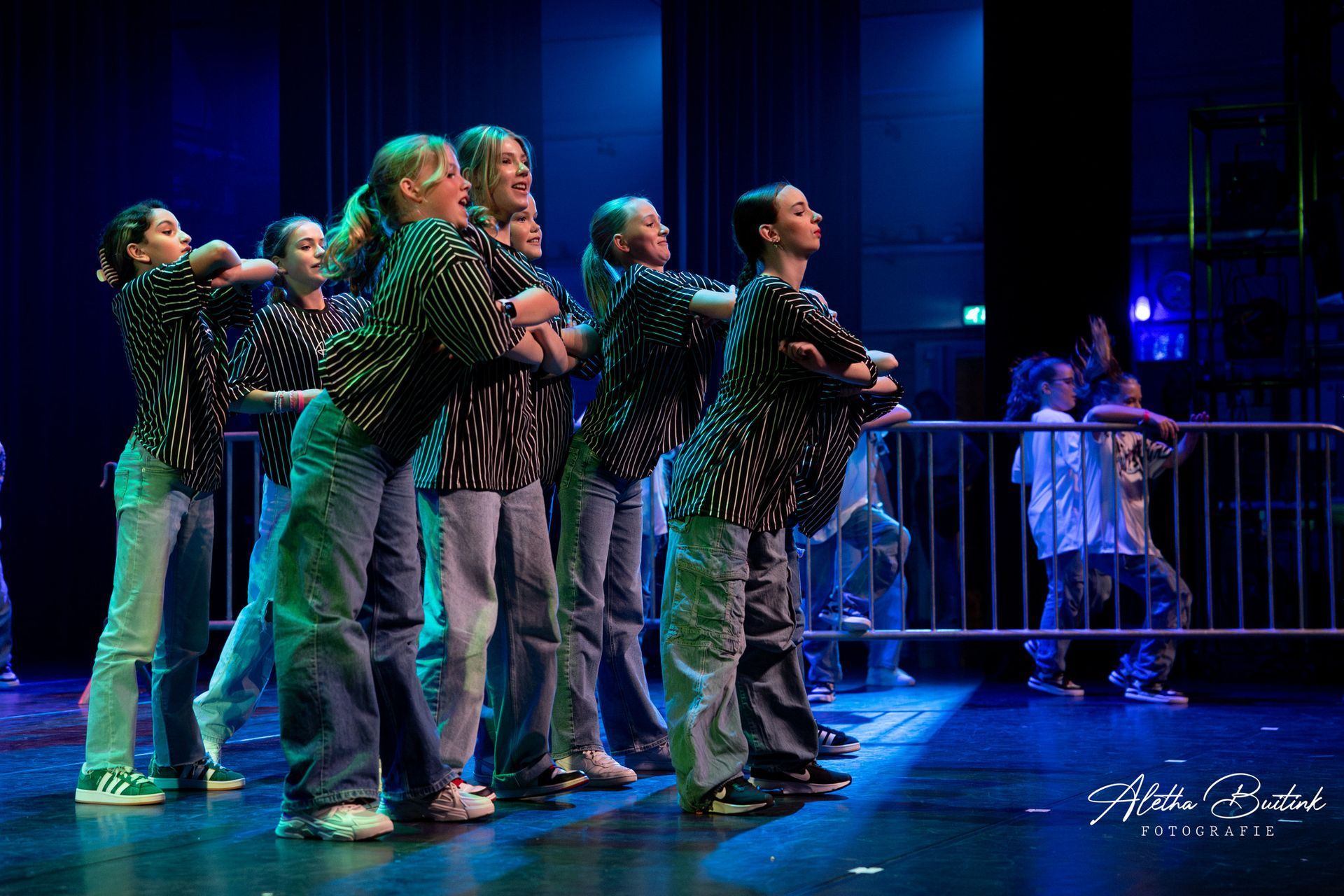 Een groep jongeren danst op een podium.